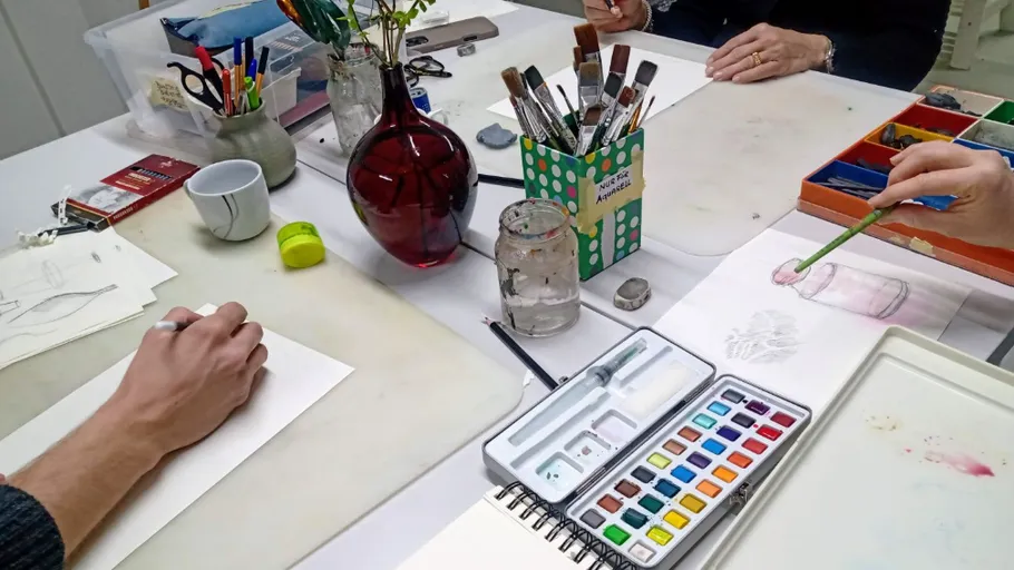Personen malen mit Aquarell am Tisch.