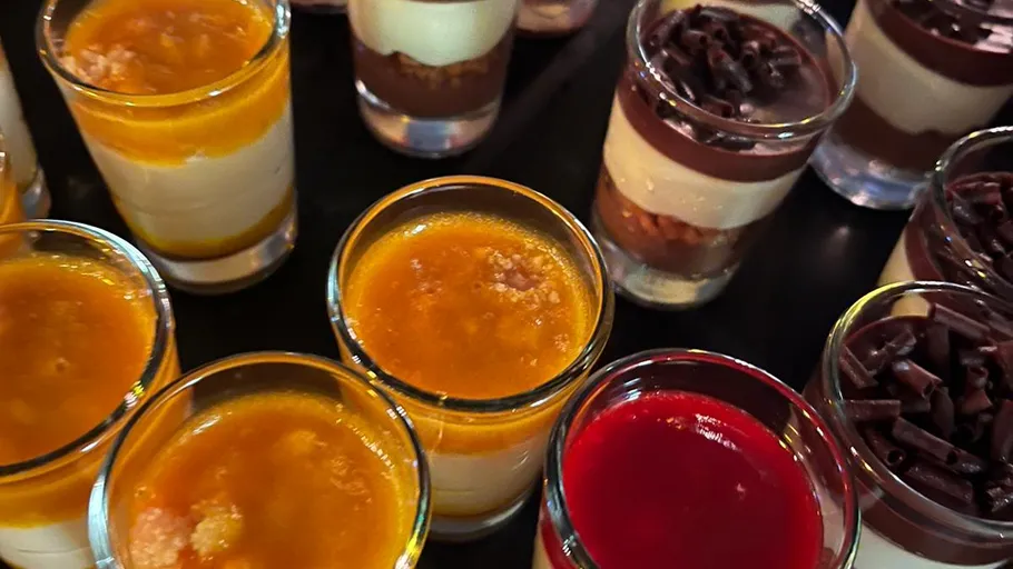 Desserts in Gläsern auf schwarzer Oberfläche.