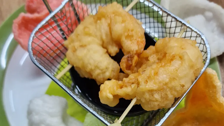 Fried shrimp skewers in small basket, colorful background.