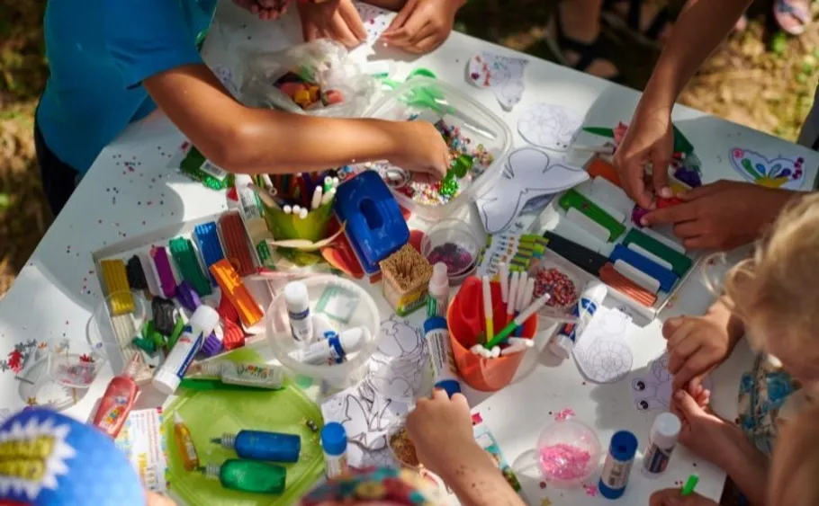 Kinder basteln mit Materialien auf einem Tisch.
