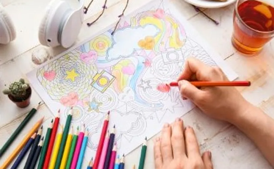 Person coloring with pencils on a table.