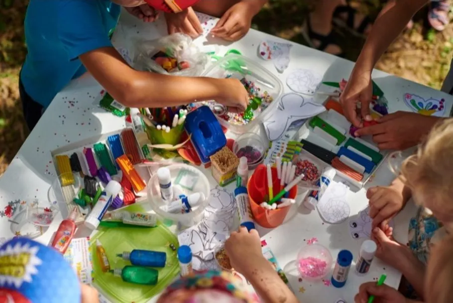 Kinder basteln mit bunten Materialien im Freien.