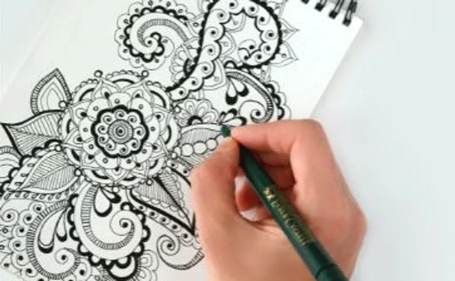 Hand zeichnet Mandala im Skizzenbuch.