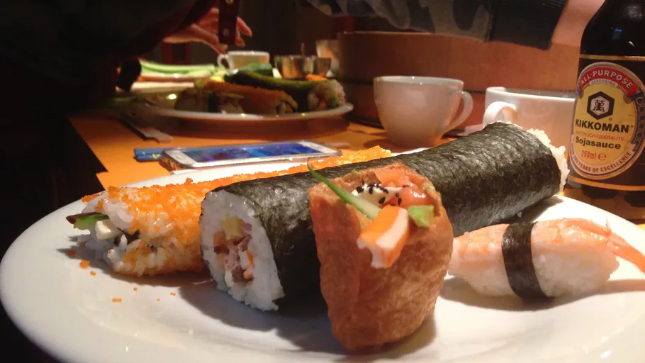 Sushiplatte mit Beilagen auf Tisch.