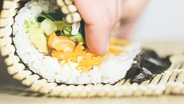 Hand rolling sushi with bamboo mat.