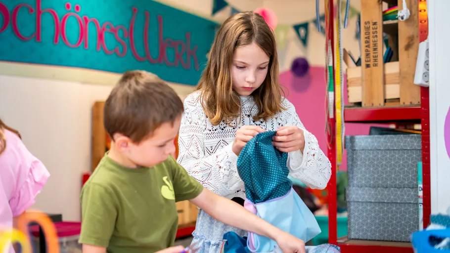 Children crafting with fabric in colorful room.