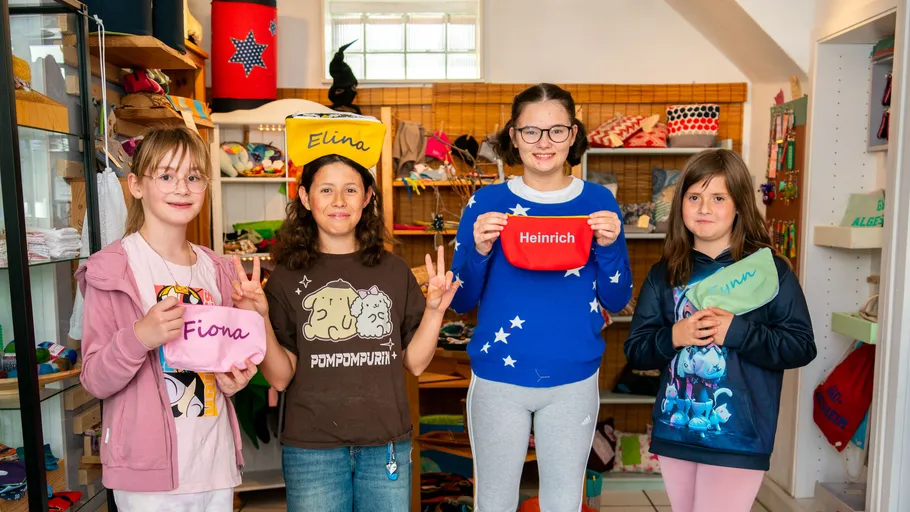 Four people holding personalized bags in a store.