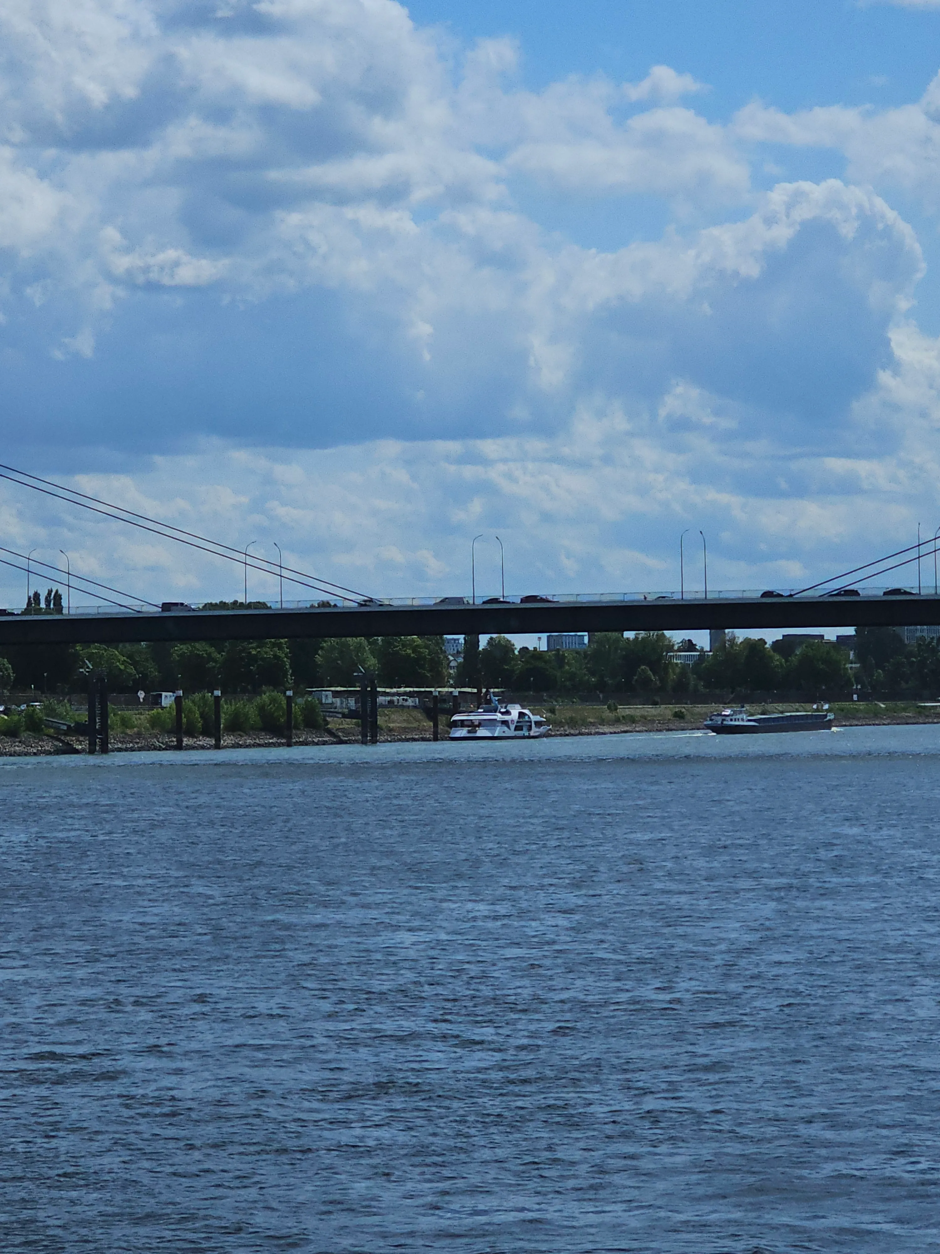 Bridge over river with boats and city skyline.