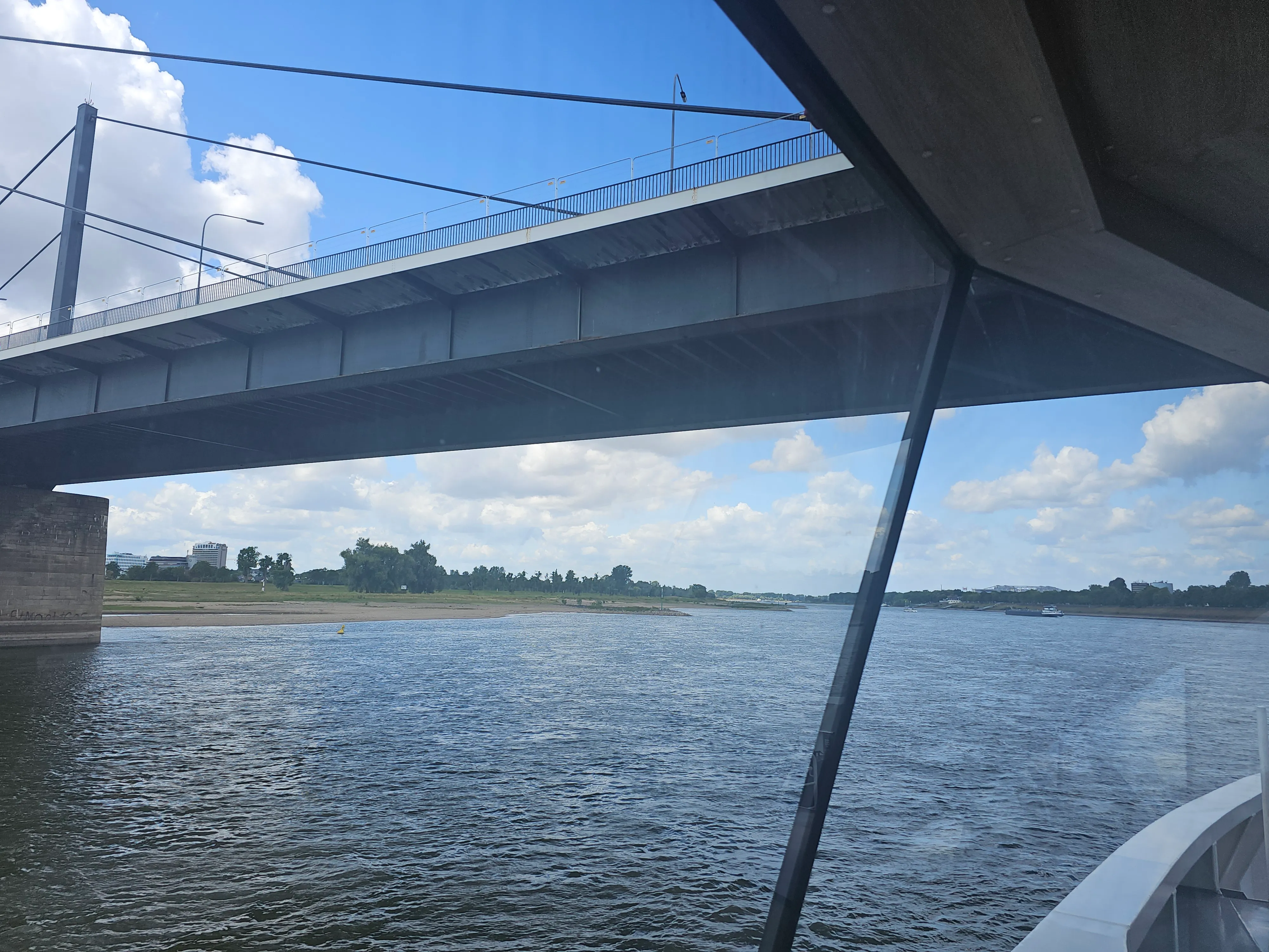 Bridge over river with cloudy sky.