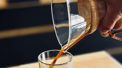 Coffee pouring from carafe into a glass.