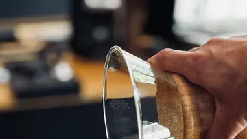 Hand holding glass pot in kitchen.