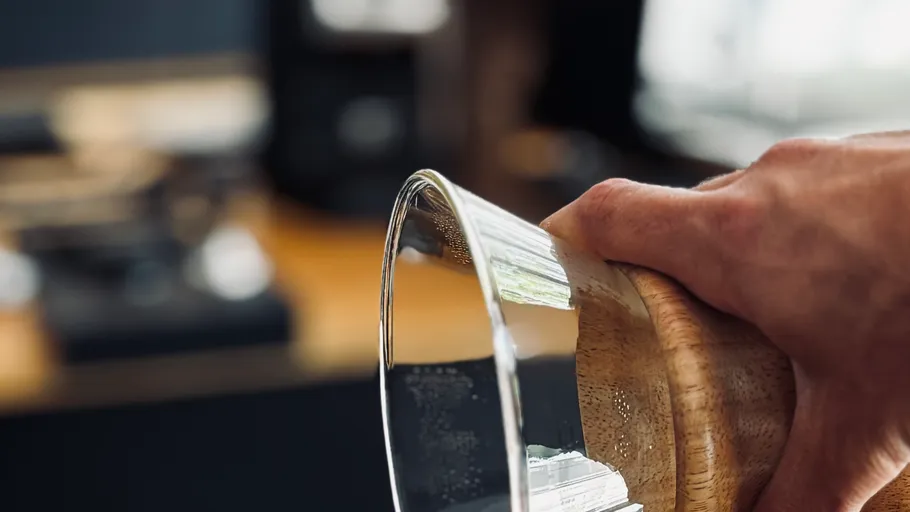 Hand holding glass pot in kitchen.