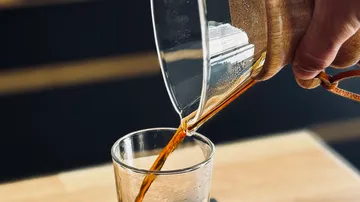 Coffee being poured into a glass cup.