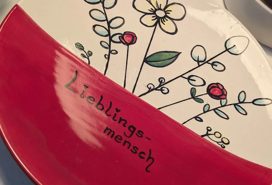 Dekorative Platte mit Blumen und "Lieblingsmensch"-Text.