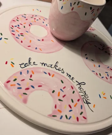 Tasse auf donutgemustertem Teller mit Text.