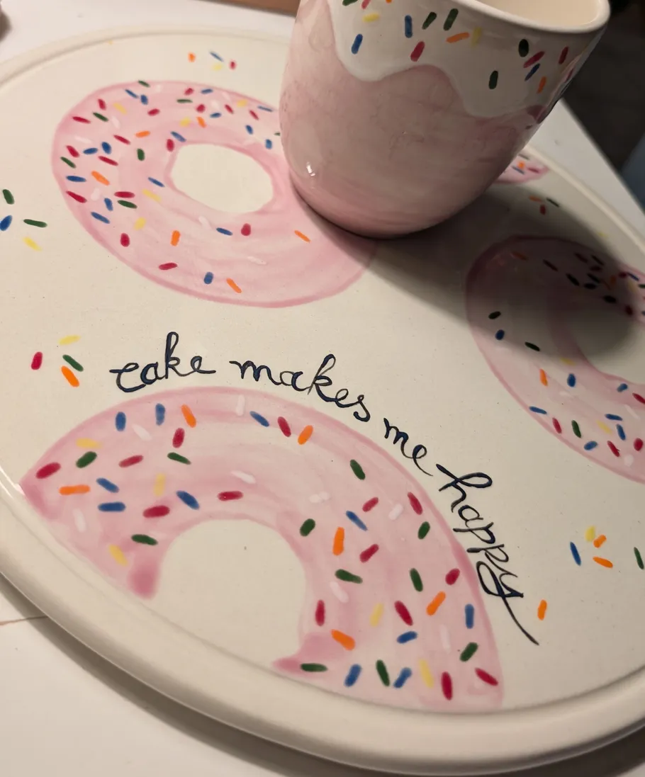 Cup on donut-patterned plate with text.