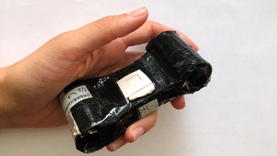 Hand hält eine schwarze, verklebte DIY-Kamera.