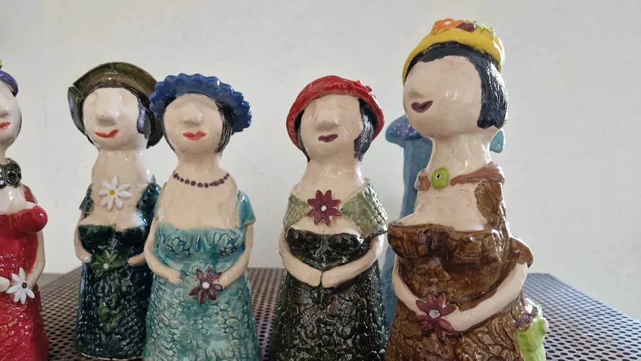Bunte Keramikfiguren auf durchlöcherter Fläche.