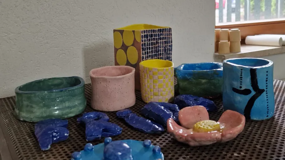 Bunte Keramikgefäße auf einem Metalltisch ausgestellt.