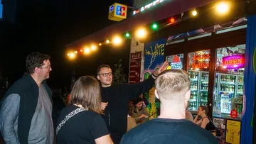 Gruppe von Menschen spricht vor beleuchtetem Laden.