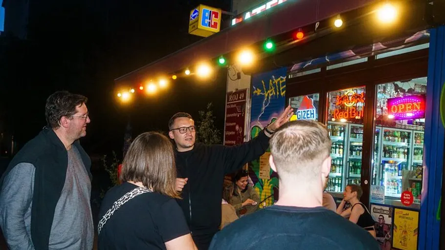 Group of people talking outside lit-up store.