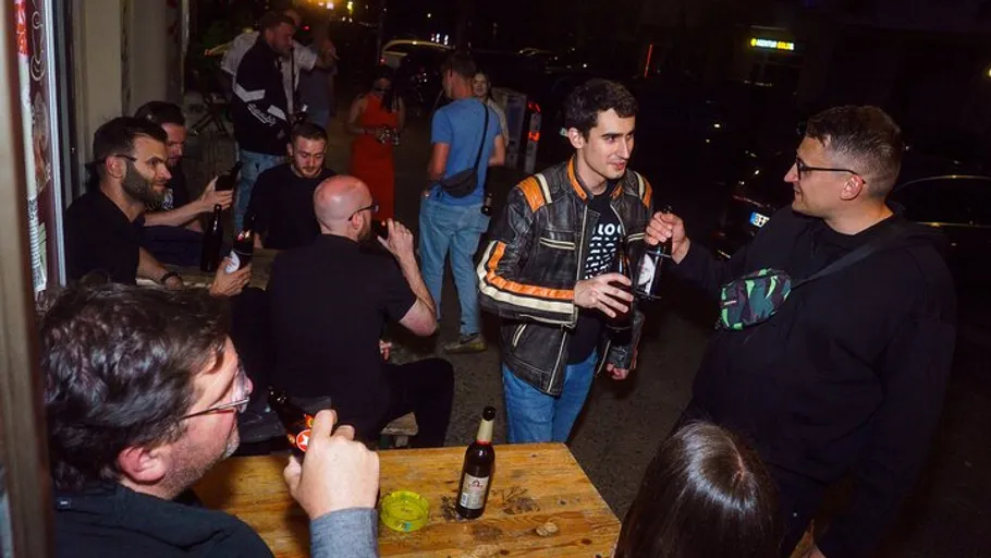 People socializing with drinks on outdoor benches.
