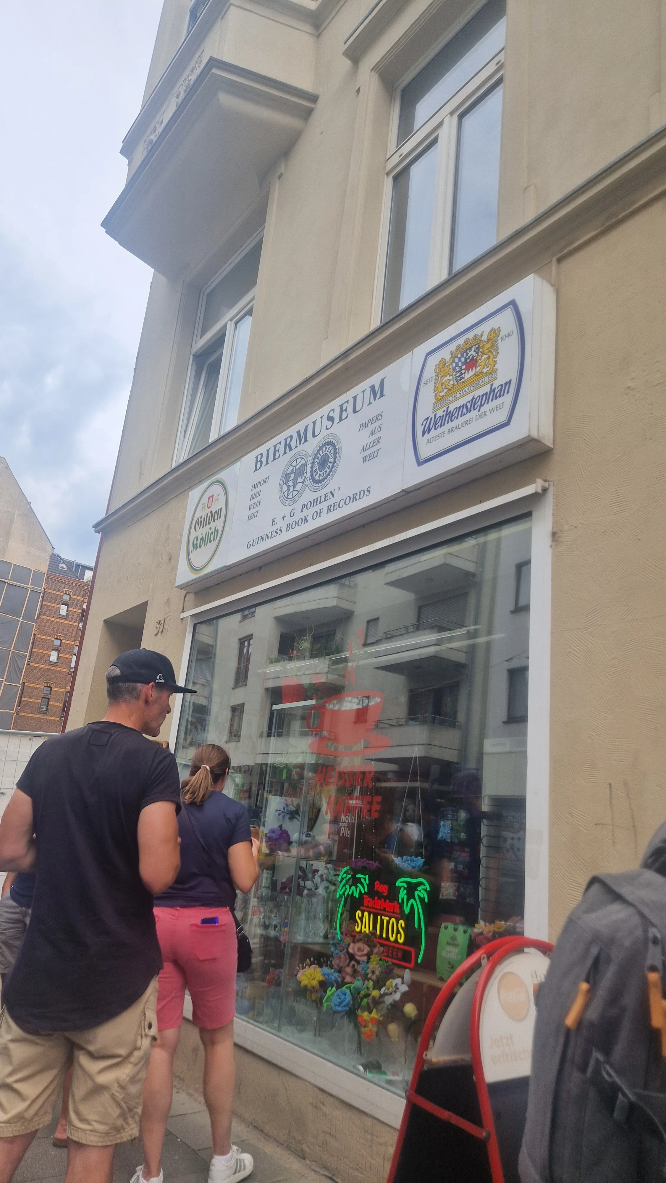 People outside a beer museum with window displays.