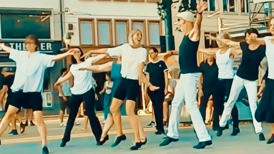 Gruppe von Menschen tanzt auf einem Stadtplatz.