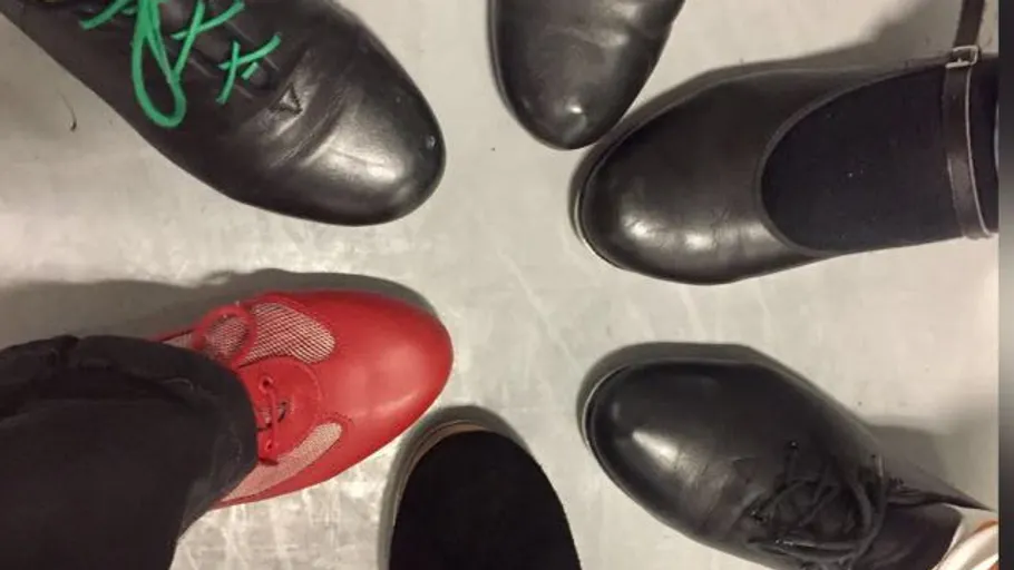 Verschiedene Schuhe im Kreis auf grauem Boden.