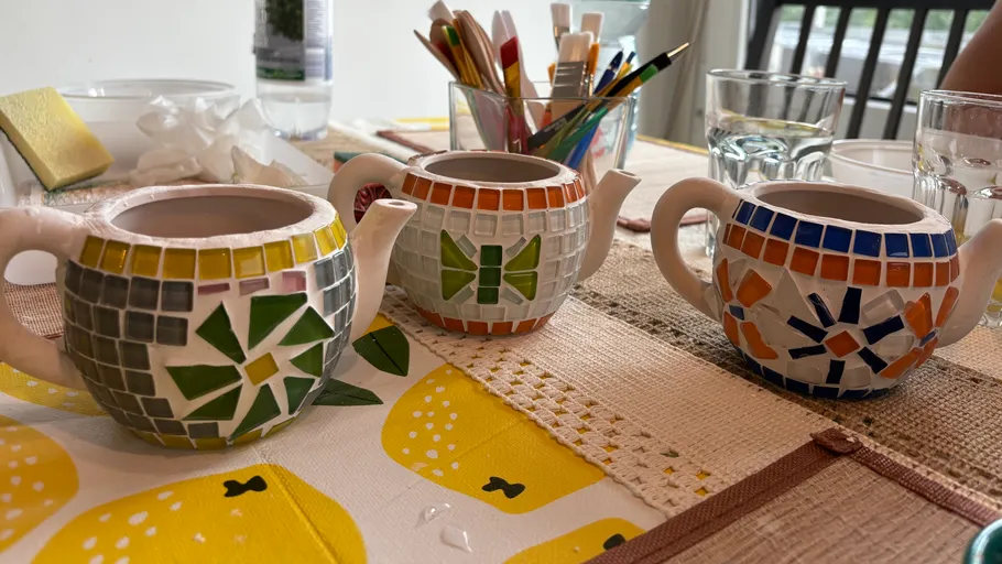 Mosaik-Teekannen auf Tisch mit Kunstbedarf.