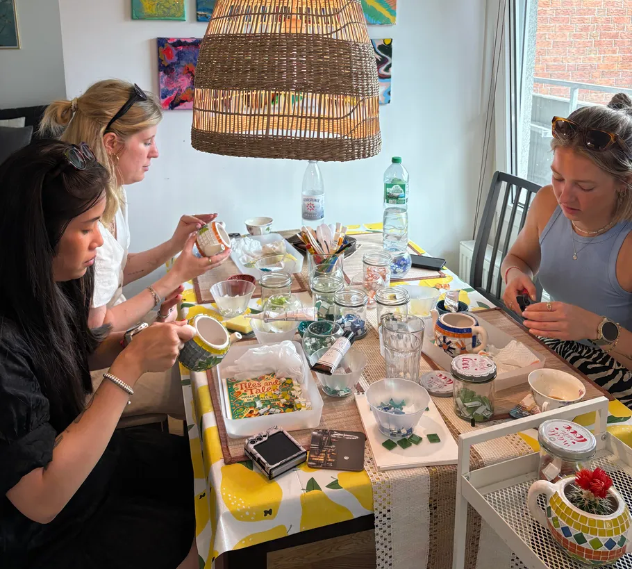 Drei Frauen gestalten Mosaikkunst an einem Tisch.