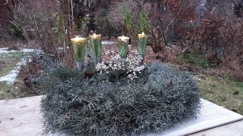 Kerzenbeleuchteter Kranz auf Außentisch im Garten.