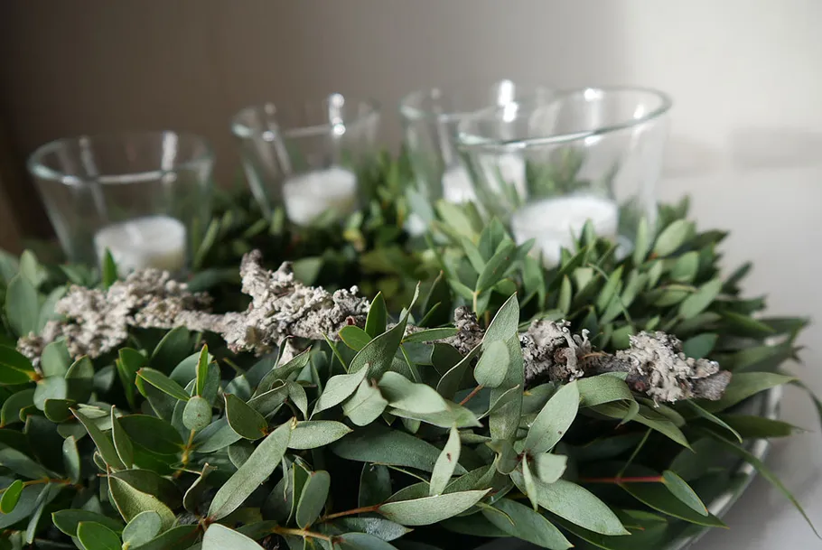 Wreath with candles on white surface.
