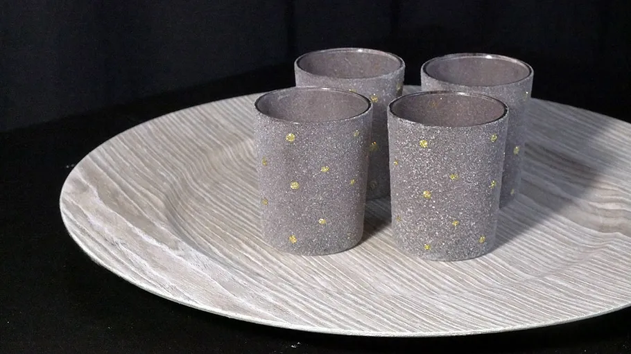 Vier graue Tassen mit gelben Punkten auf Tablett.