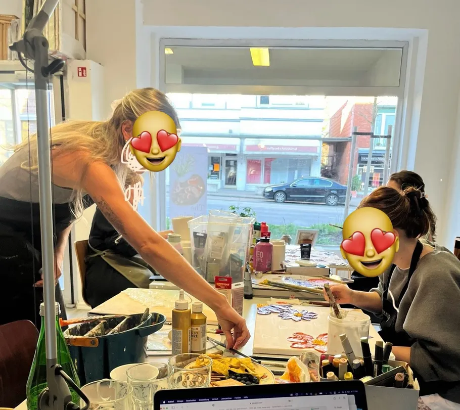 Personen malen an einem Tisch mit Materialien.