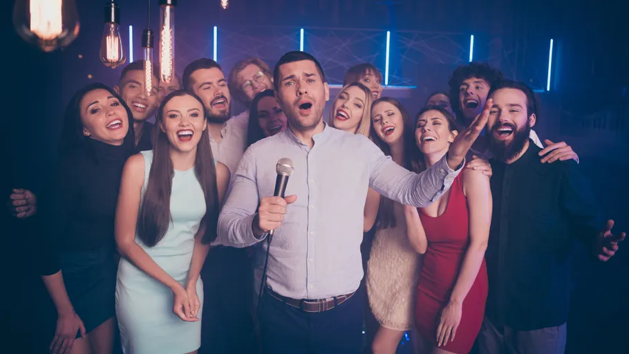Gruppe singt mit Mikrofon in einem Nachtclub.