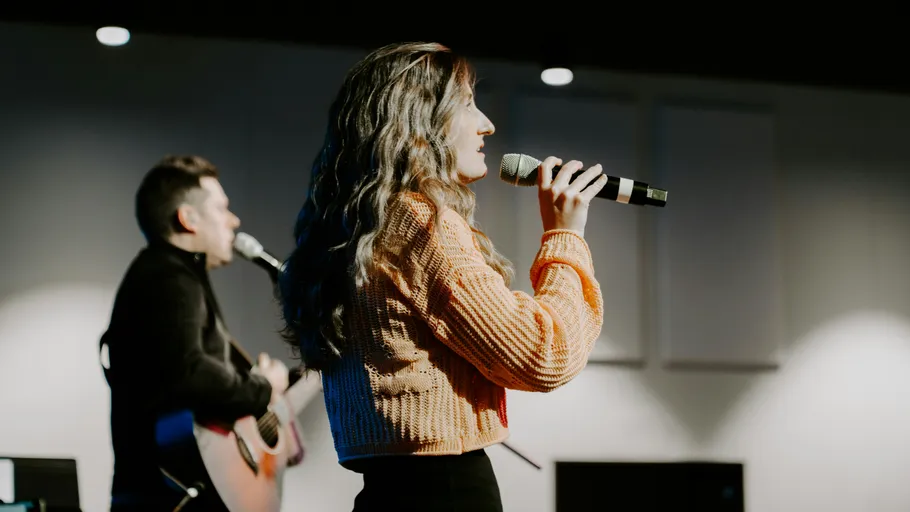 Woman and man singing on stage.
