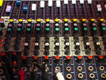 Mischpult mit verschiedenen Reglern und Farben zur Audiokontrolle.