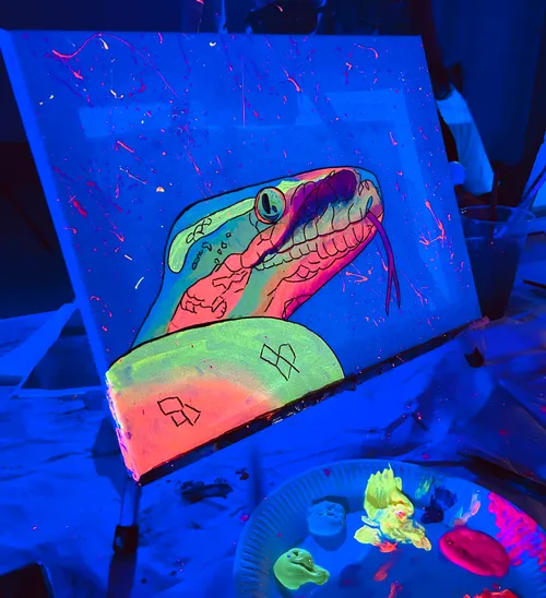 Neon-Schlangengemälde unter Schwarzlicht, unordentlicher Tisch.