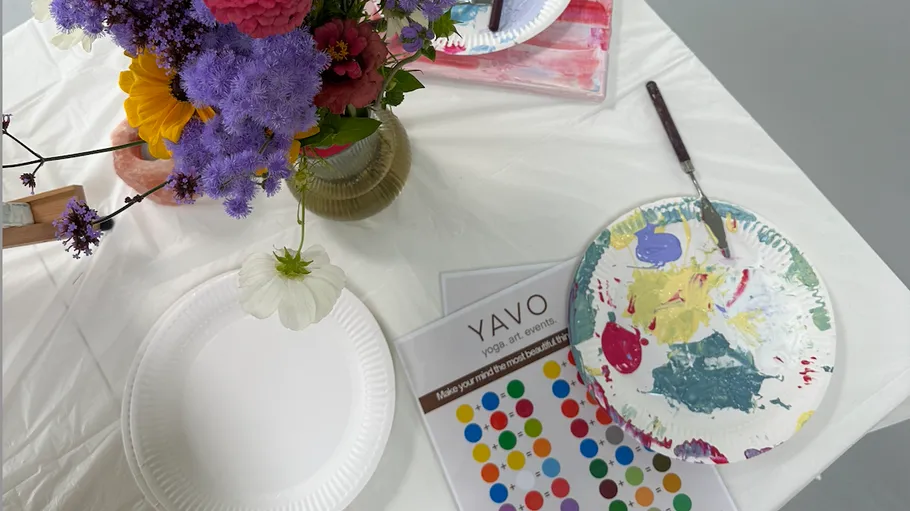 Flowers and painted plates on art table.