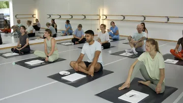 Menschen sitzen auf Yogamatten in einem Studio.