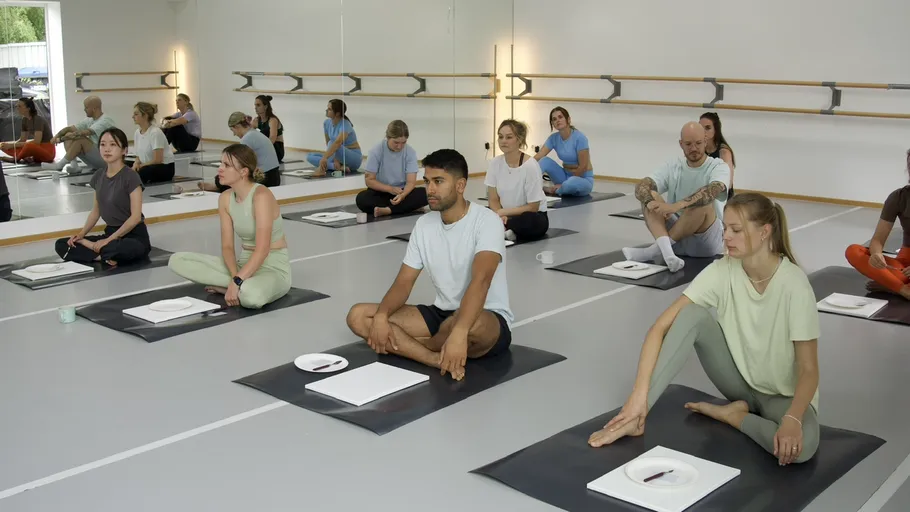 Menschen sitzen auf Yogamatten in einem Studio.