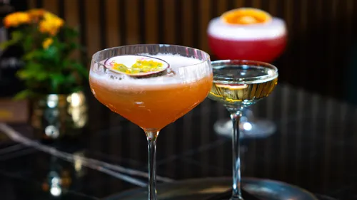 Three cocktails with fruit garnish on a table.