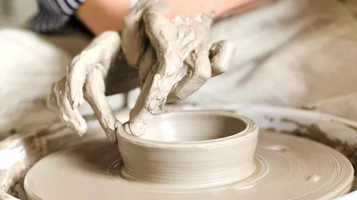 Hands shaping clay on a pottery wheel.