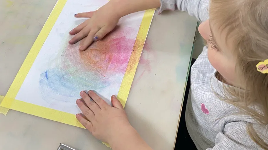 Child painting with chalk on paper.