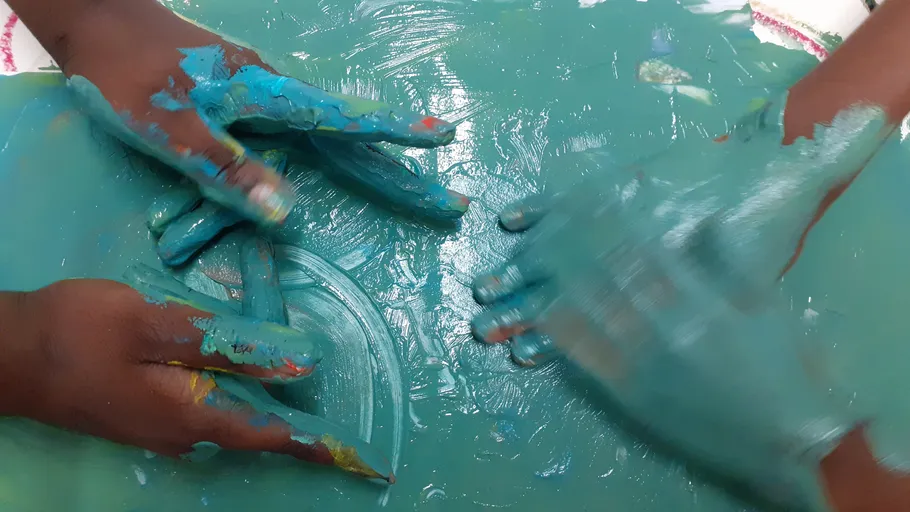 Kinderhände spielen mit blauer Farbe.