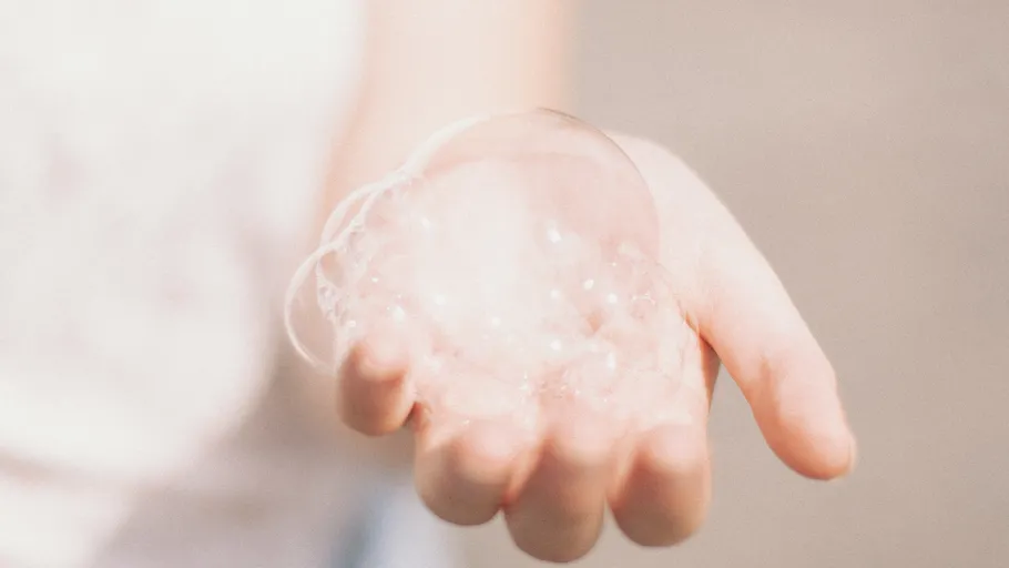 Soap bubbles held in a hand outdoors.