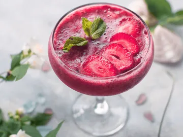 A drink with berries and mint in a glass.