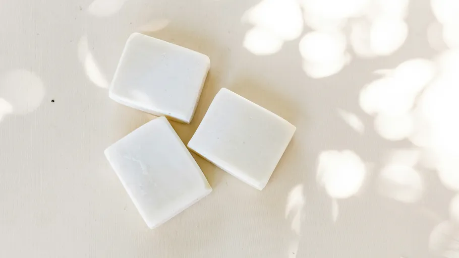 Three white soap bars on a light surface.