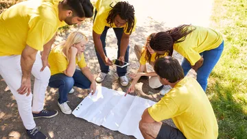 Group examining a map outdoors on a path.